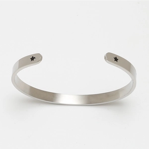 Close-up of silver open cuff bracelet featuring two black star motifs on ends