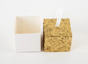 Detail of white gift box and golden glitter cube box with satin ribbon handle
