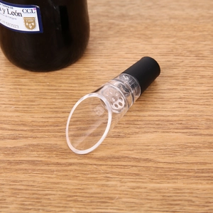 Detail of red wine aerator pourer with acrylic tube and silicone stopper on wood base
