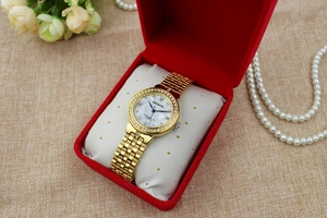 Close-up of gold diamond-set women watch with Roman numerals in a red velvet gift box