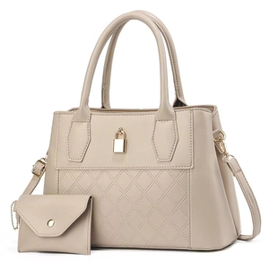 Set borsa a mano beige trapuntata con lucchetto dorato e pochette coordinata su sfondo bianco