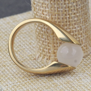 Modern 18K gold-plated stainless steel ring with white cat eye stone on woven texture