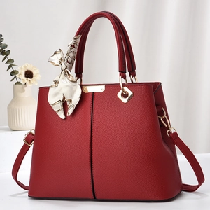 Elegant red lychee leather trapezoid handbag with gold hardware and printed scarf