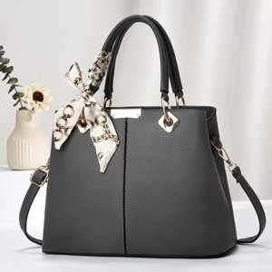 Dark grey pebble leather tote bag with silk scarf accent and golden hardware on white fabric