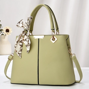 Close-up of light green lychee leather handbag with decorative silk scarf and gold hardware