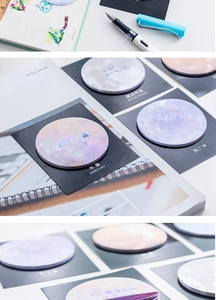 Macro detail of round planetary sticky notes showing realistic celestial textures on a desk