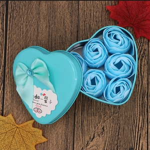 Blue heart-shaped tin box with six soap roses and a silk bow on dark wood background