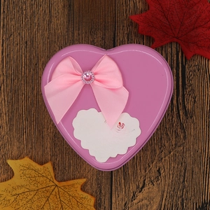 Detail of purple heart-shaped tin box with pink silk bow and romantic text on wood