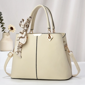 Close-up of beige lychee texture handbag with silk scarf and golden metal hardware
