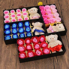 Gift set featuring soap roses and plush bears in colorful boxes on wooden floor