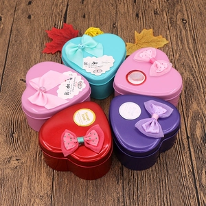 Macro shot of heart-shaped tin boxes with ribbons and Sweet Love stickers on wood