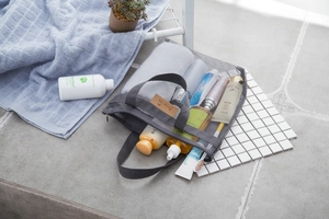 Dettaglio della borsa da viaggio in rete grigia con manico e cerniera in bagno pulito