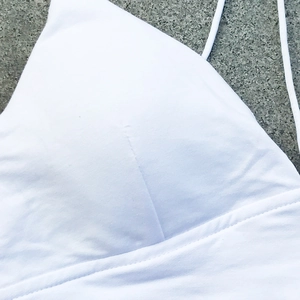 Vista detallada del crop top blanco de club con tirantes finos y detalles de doble costura