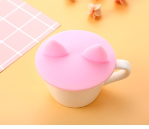 Macro view of cute pink silicone cup lid with 3D cat ear design on a ceramic mug