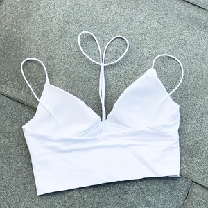 Vista detallada de un top corto blanco con cuello en V y diseño de tirantes simétricos