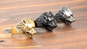 Détail de bagues tête de loup en or, noir et argent sur fond de bois rustique