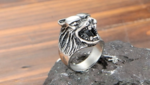 Détail d'une bague tête de loup sculptée posée sur une roche avec une finition vintage