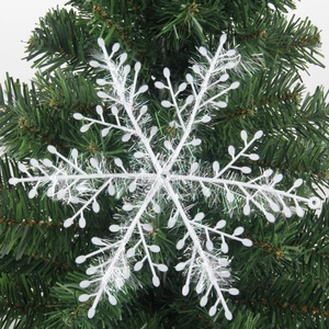 Sparkling white glitter snowflake ornament hanging on a green Christmas tree branch