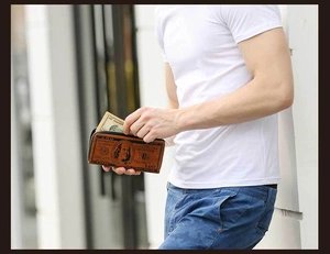 Detailed view of long dollar bill pattern wallet held by a person in outdoor setting