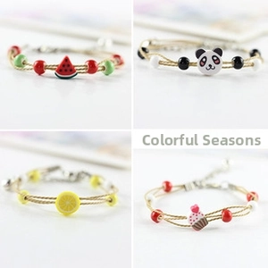 Detail of four handmade beaded bracelets with cute panda, watermelon and lemon charms