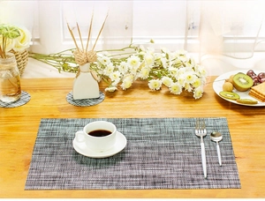 Close-up of gray woven PVC placemat and coasters set on a wooden dining table