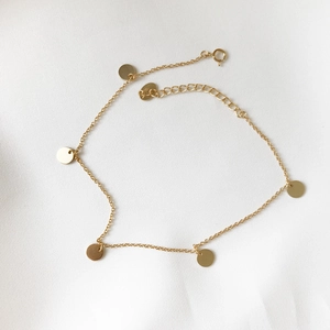 Detail of a 925 sterling silver anklet with delicate gold-plated round disc charms
