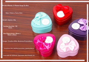 Detail view of heart-shaped tin boxes with silk bows and three scented soap roses