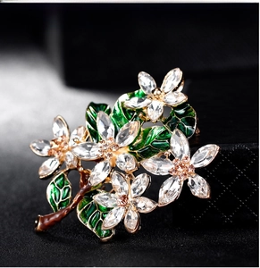 Detail of vintage floral enamel brooch with green leaves and sparkling crystals