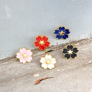 Detailed view of five colorful cherry blossom enamel brooches with golden metal edges