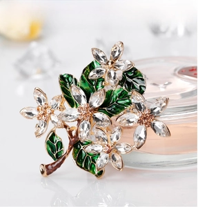 Detail of vintage flower brooch with green enamel leaves and sparkling crystal petals