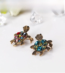 Close-up of vintage gold turtle brooches with colorful faceted rhinestones on a white base