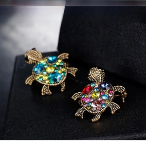 Macro shot of vintage turtle brooches with colorful gemstones on black jewelry box