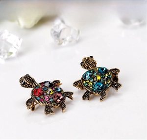 Close-up of vintage turtle brooch featuring colorful rhinestones and gold metal texture