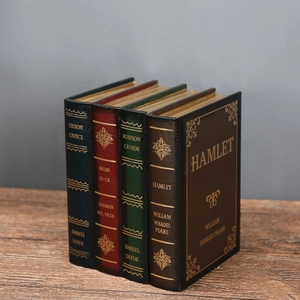 Close-up of four vintage faux leather decorative books with gold foil lettering on a wood desk