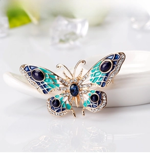 Detailed macro of a gold butterfly brooch with blue enamel wings and sparkling crystals