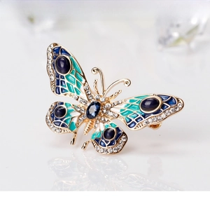 Detailed close-up of a colorful enamel butterfly brooch with blue gemstones and gold trim