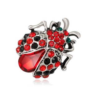 Macro shot of silver ladybug brooch with red faceted crystals and sparkling rhinestones