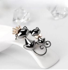 Détail de broche chat avec couronne dorée et nœud papillon aux strass étincelants