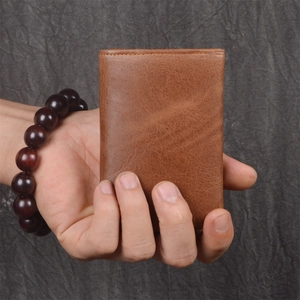 Brown vintage leather short wallet held in hand showing natural texture and minimalist style