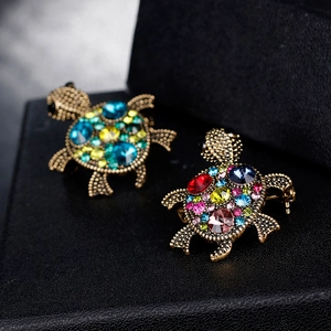 Vintage gold sea turtle brooch set with colorful crystals on a black leather stand