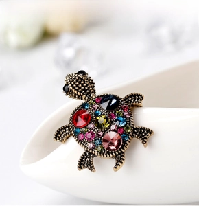 Macro detail of vintage gold turtle brooch with colorful rhinestones and ruby accents