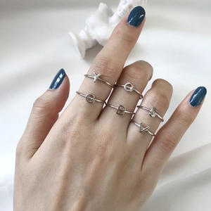 Minimalist 925 sterling silver alphabet rings worn on fingers with blue nail polish