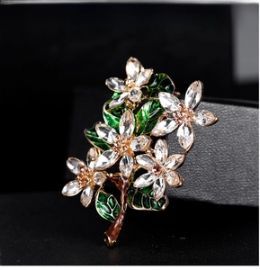 Detailed macro view of vintage flower brooch with crystals and green enamel leaves