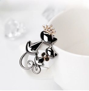 Détail d'une broche chat mignonne avec couronne et nœud sur le bord d'une tasse