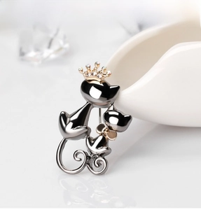 Détail d'une broche chat noir avec couronne en strass et petit nœud papillon doré
