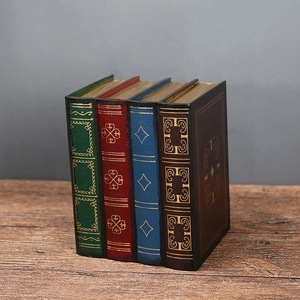 Detail of four vintage-style faux book storage boxes with gold-foil patterns and leather texture