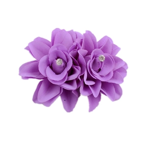 Detailed macro view of purple fabric double rose hair clip with sparkling rhinestones