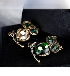 Dettaglio di spille a gufo vintage con cristalli sfaccettati verdi e color champagne
