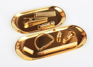 Detailed set of polished brass oval jewelry trays with gold stationery and metal clips