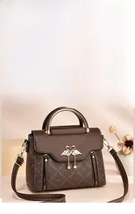 Detailed view of the brown monogram tote with golden swan clasp and pearl tassel